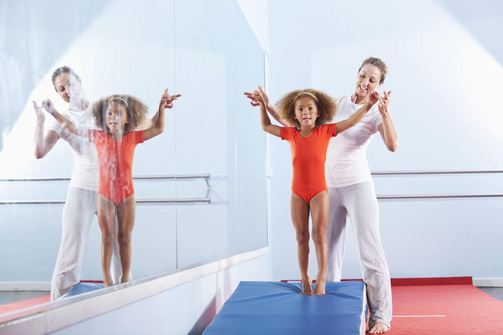 a gymnastic coach helping a young student