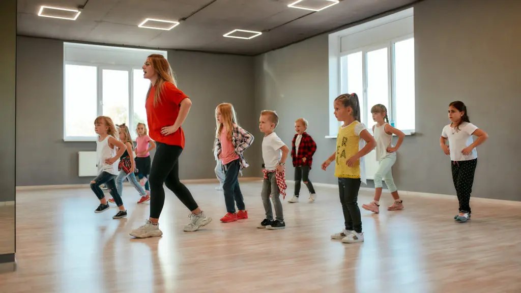 Group of little boys and girls dancing while having choreography class in the dance studio. Female dance teacher and children