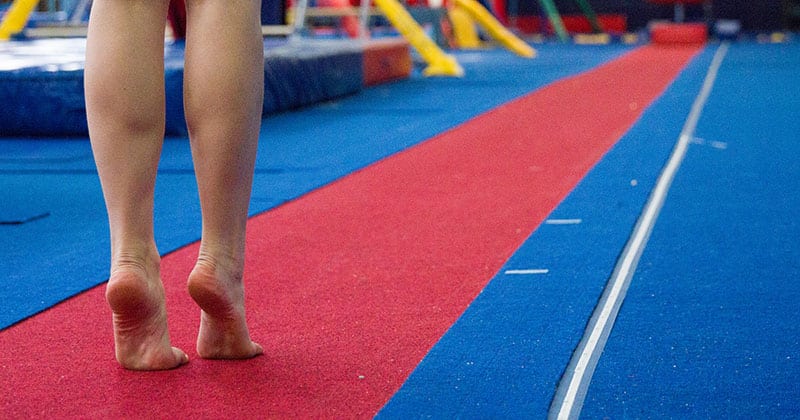 Close-up of legs on gymnastics floor about to run