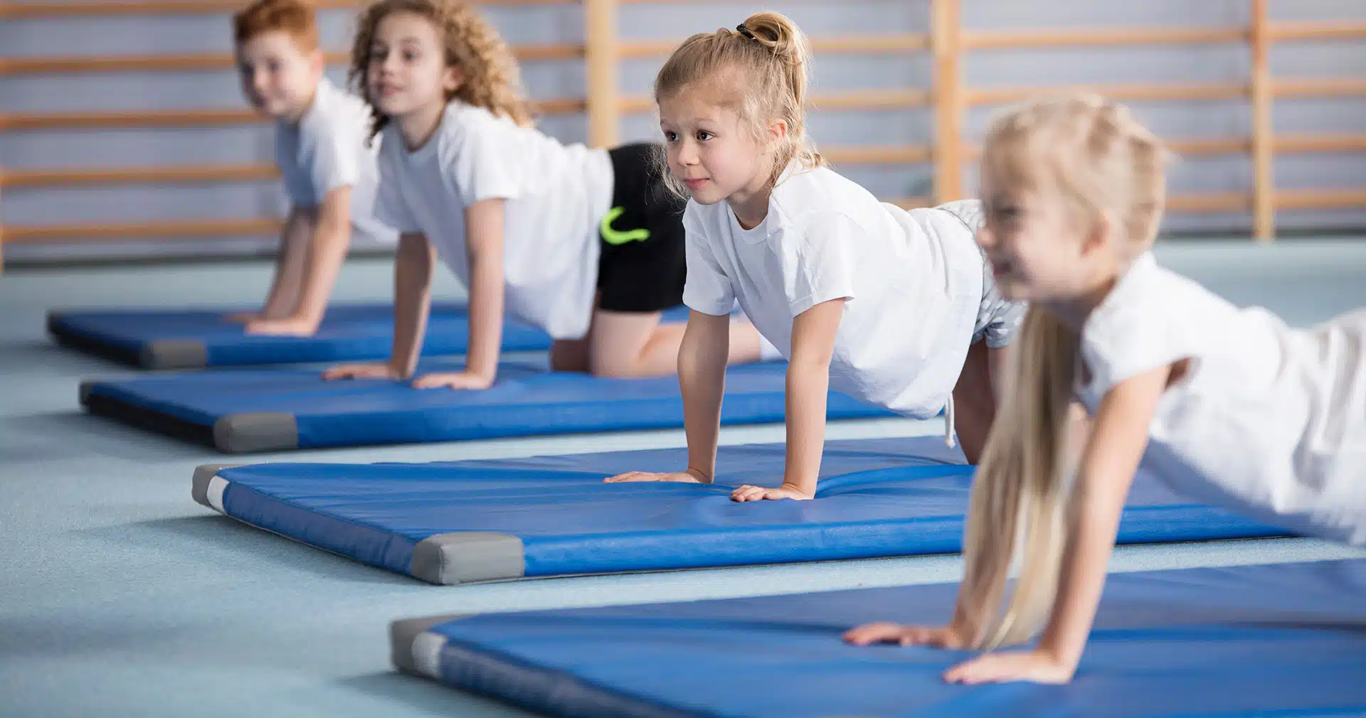 Four kids in gymnastics class on floor mats