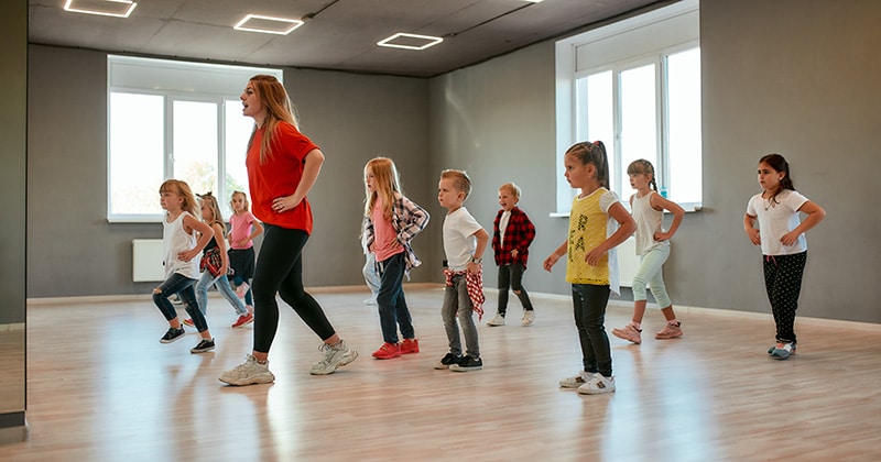 Kids take a dance class led by adult