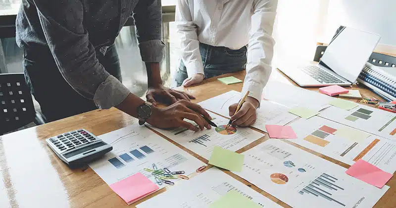 Two people stand over business plans