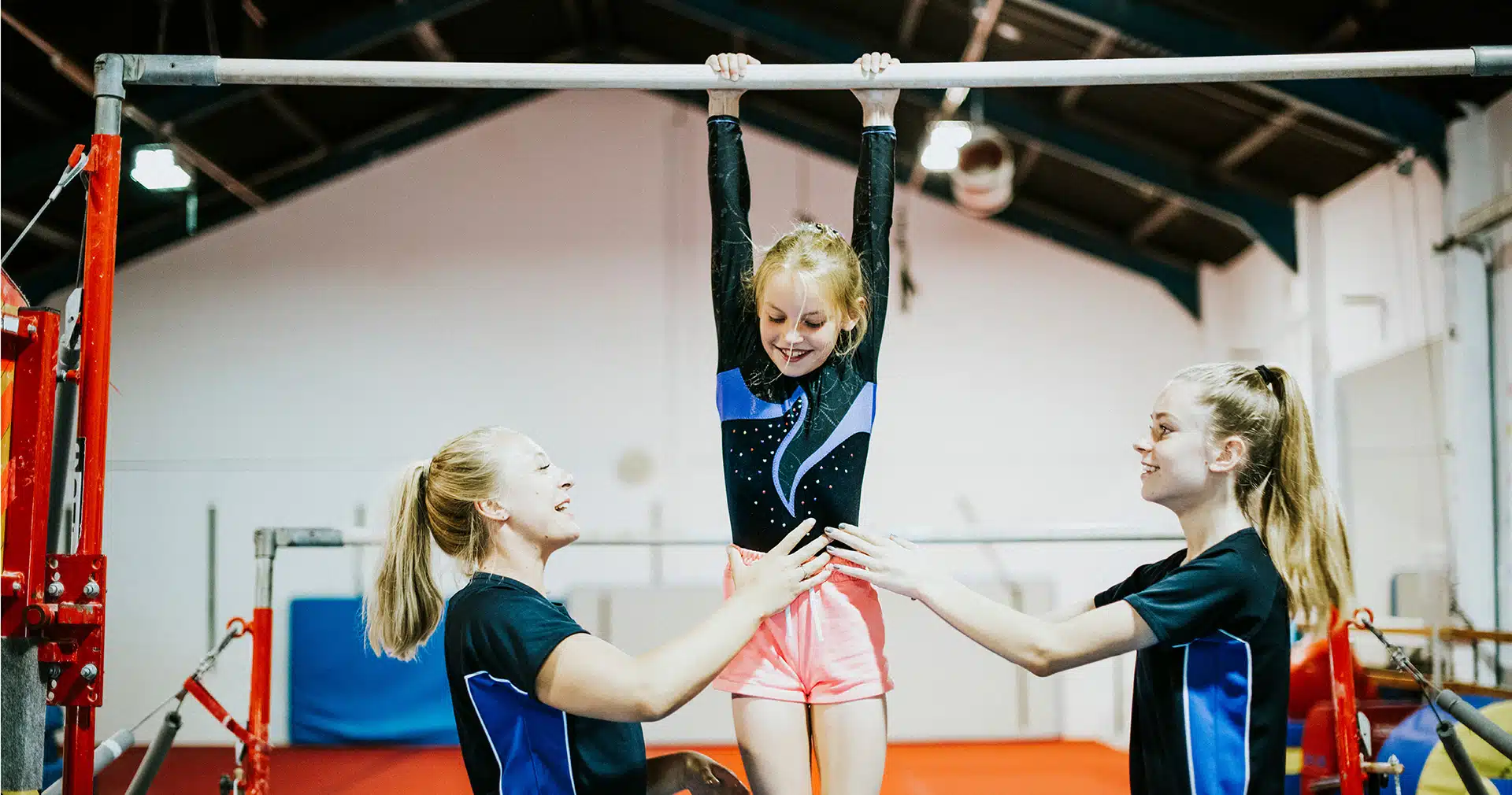 Two women coach a young gymnast