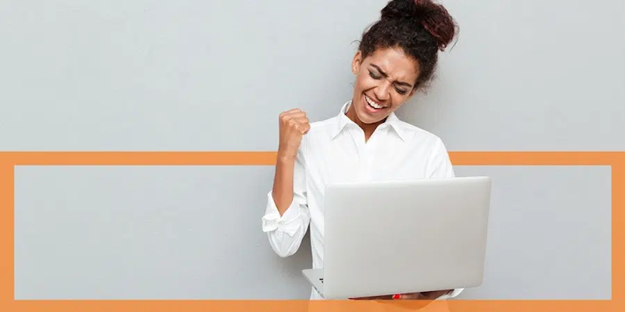 a person pumping their fist while looking at a laptop