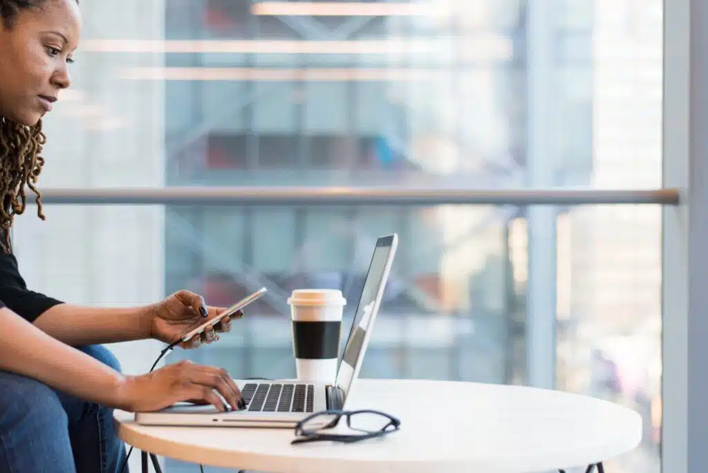 a person on a computer looking at their phone