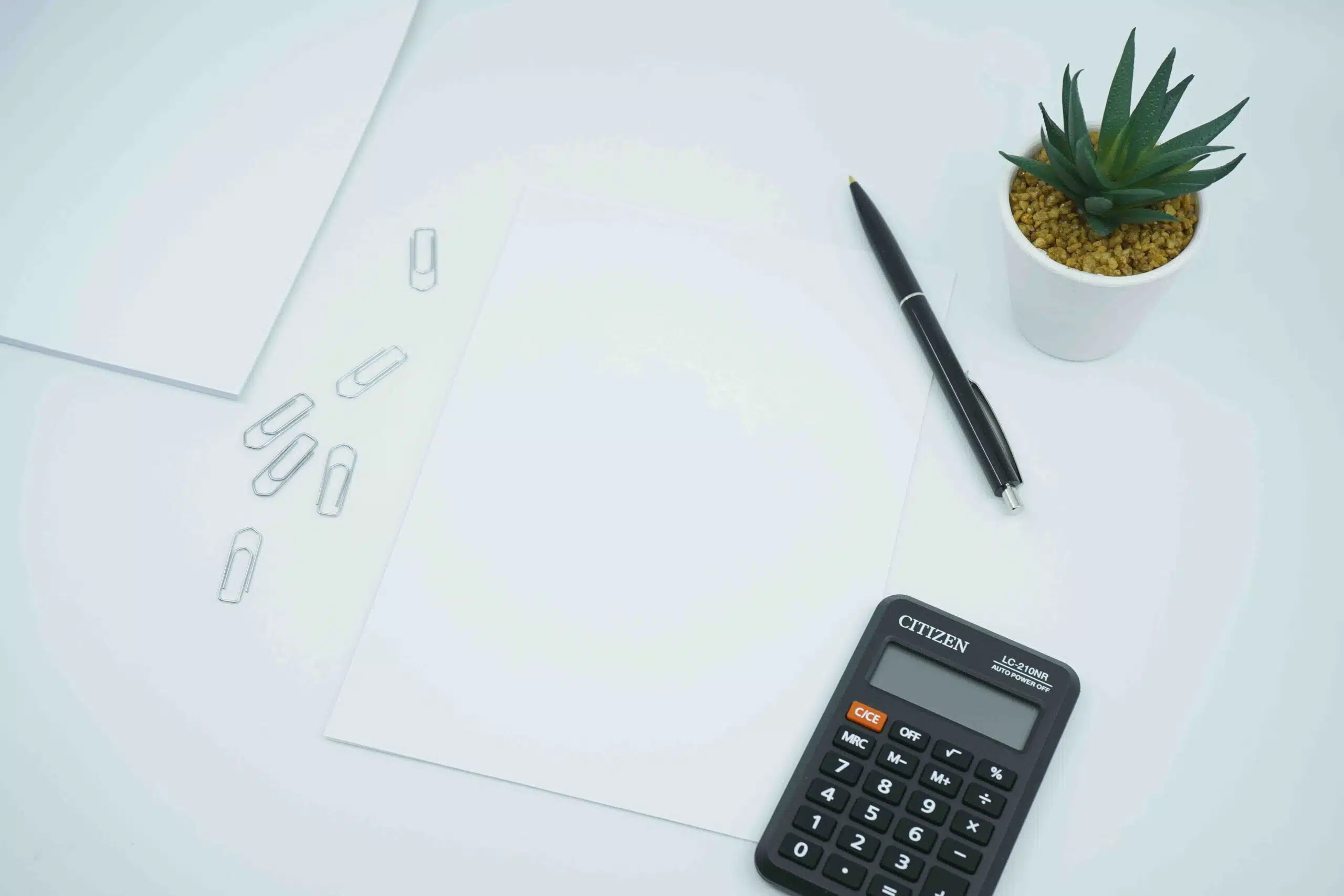 a calculator next to a pen on a table