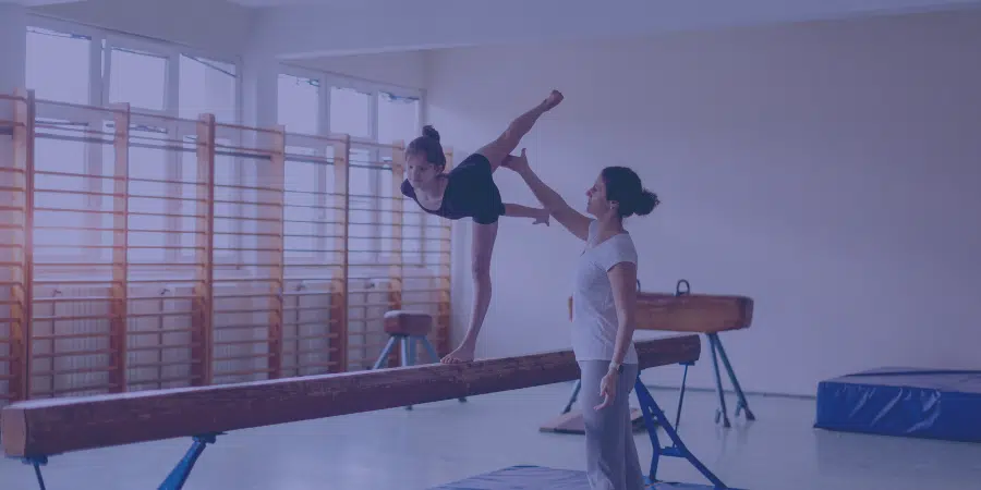 an instructor helping a young person with their gymnastics