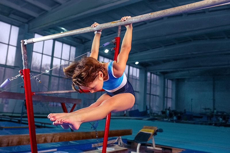 a young girl on a parallel bar doing gymnastics