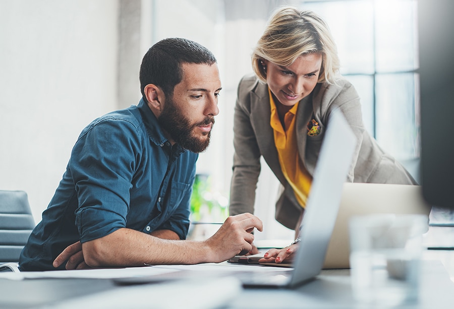 man and woman looking at a laptop screen in an office